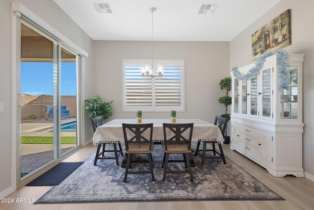 dining space with baseboards, a notable chandelier, visible vents, and wood finished floors