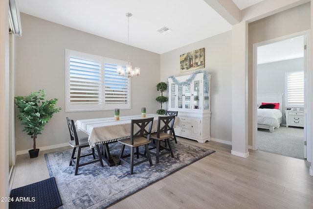 dining room featuring baseboards, an inviting chandelier, visible vents, and light wood-style floors