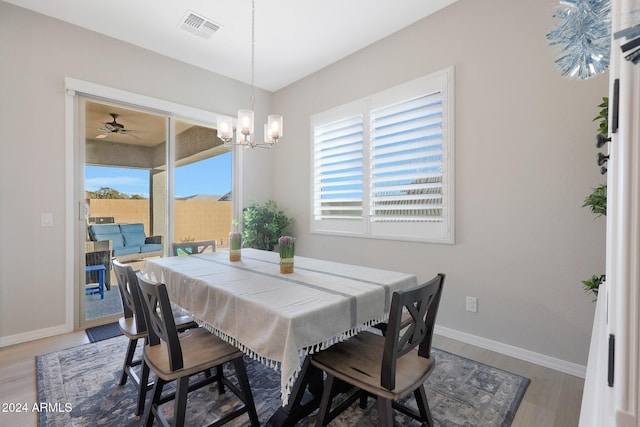 dining room with baseboards, light wood finished floors, a chandelier, and visible vents