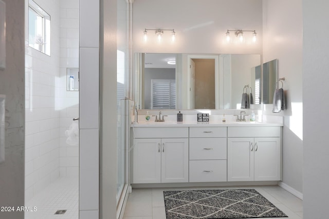 full bath featuring double vanity, tile patterned floors, tiled shower, and a sink