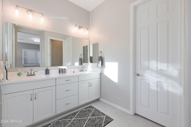 bathroom featuring double vanity, baseboards, tile patterned flooring, and a sink