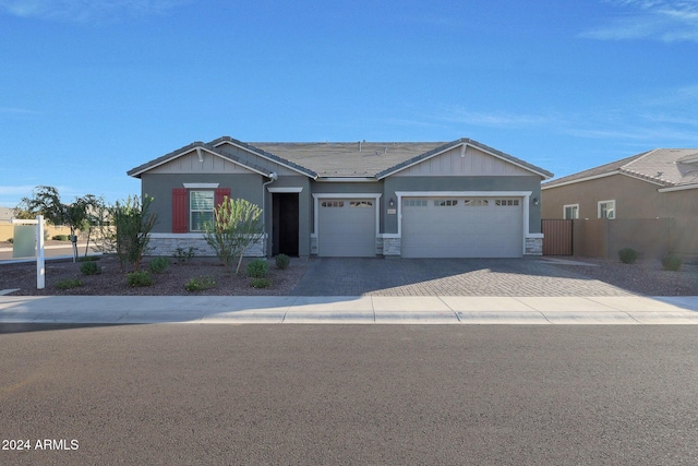 view of front of property with fence, stone siding, a garage, stucco siding, and decorative driveway