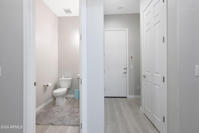 bathroom featuring baseboards, toilet, wood finished floors, and visible vents