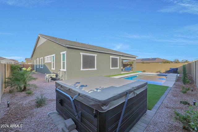 rear view of property featuring a fenced backyard, a fenced in pool, stucco siding, and a hot tub