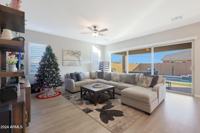 living area featuring light wood-style floors, a healthy amount of sunlight, a ceiling fan, and visible vents