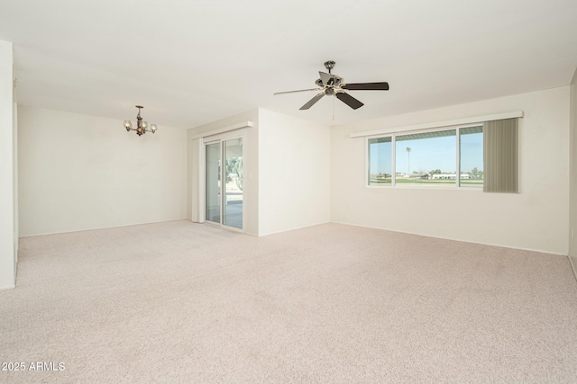 spare room with ceiling fan with notable chandelier, carpet floors, and a wealth of natural light