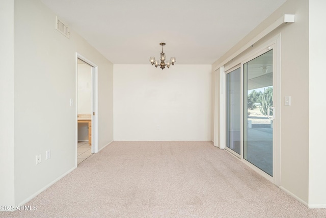 empty room featuring light carpet and an inviting chandelier