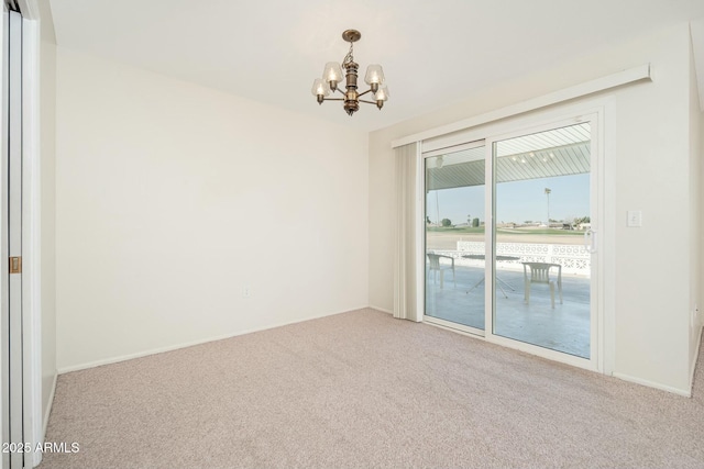 carpeted spare room featuring a chandelier