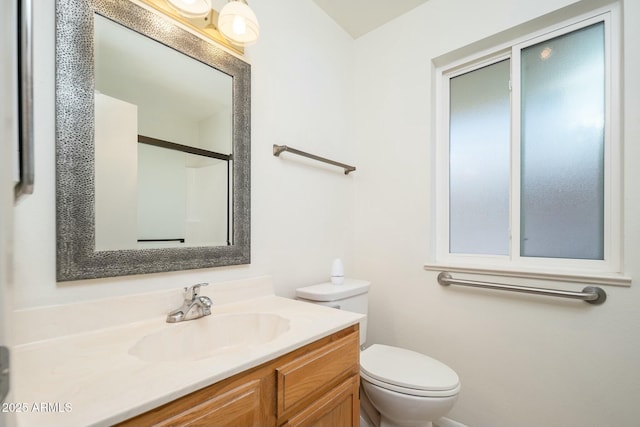 bathroom featuring vanity, toilet, and a shower with door