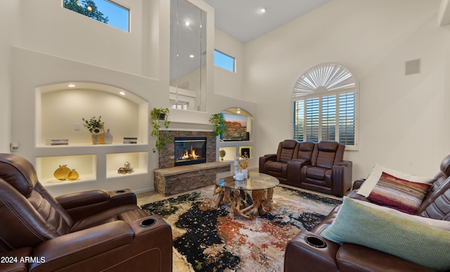 living room featuring built in features, a fireplace, and a high ceiling