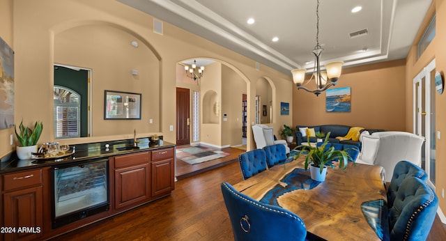 dining space with a notable chandelier, dark hardwood / wood-style flooring, beverage cooler, and a tray ceiling