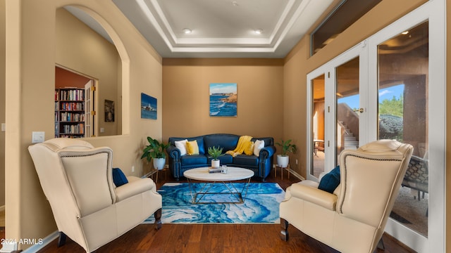 living room with a raised ceiling and dark hardwood / wood-style flooring