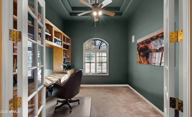 carpeted office featuring ceiling fan and a tray ceiling