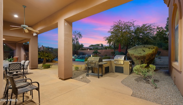 patio terrace at dusk featuring area for grilling and ceiling fan