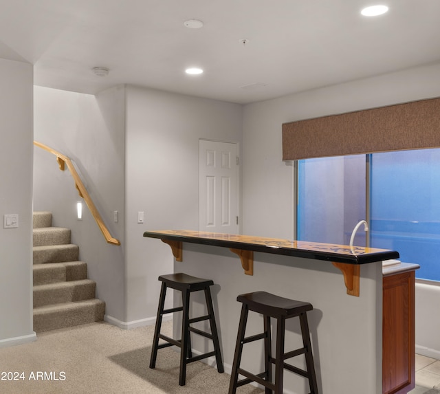 kitchen with a kitchen breakfast bar and light colored carpet