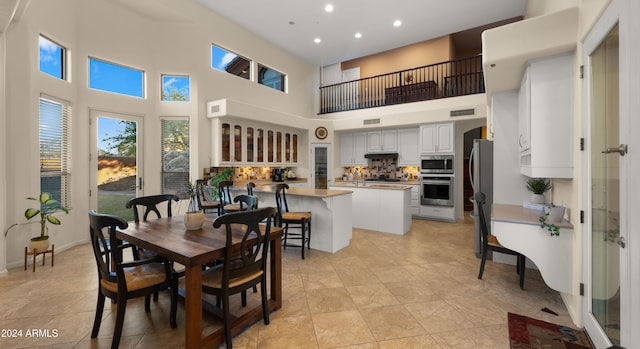 dining room with a towering ceiling and light tile patterned flooring