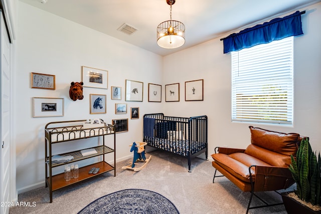 bedroom featuring a nursery area, a notable chandelier, and carpet flooring