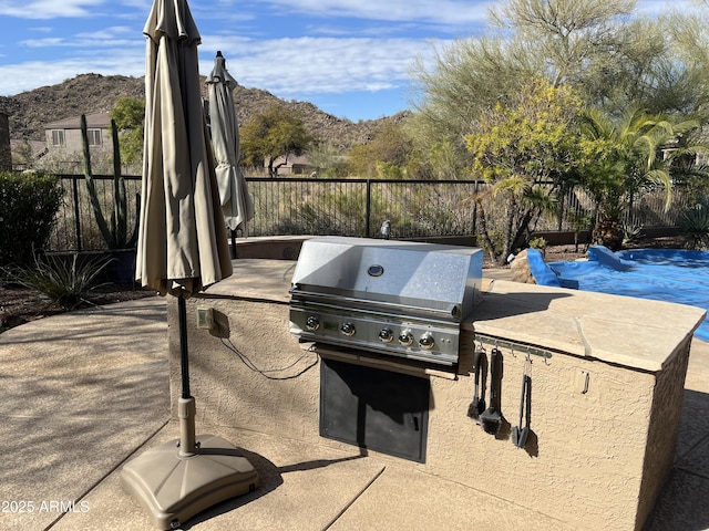 view of patio featuring exterior kitchen, area for grilling, a mountain view, and a covered pool