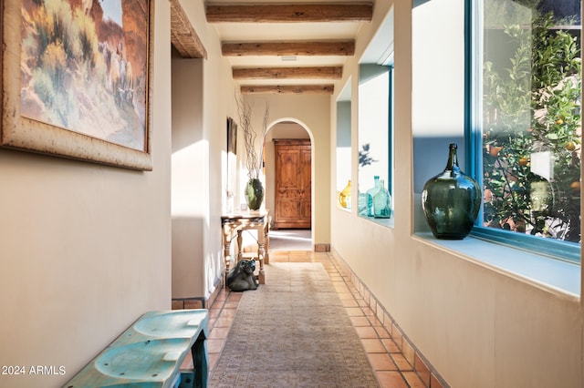 hallway with light tile flooring and beamed ceiling