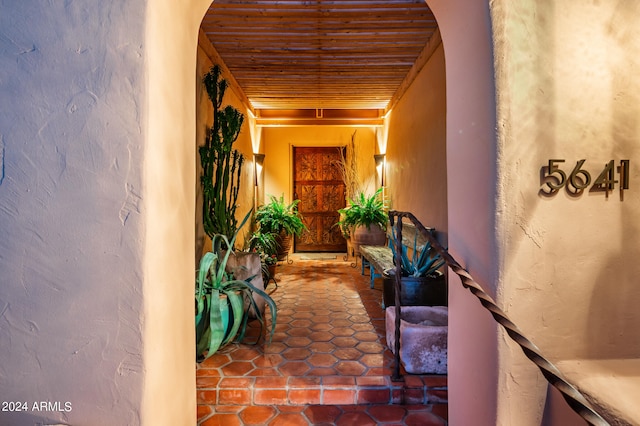 corridor with wood ceiling and dark tile flooring