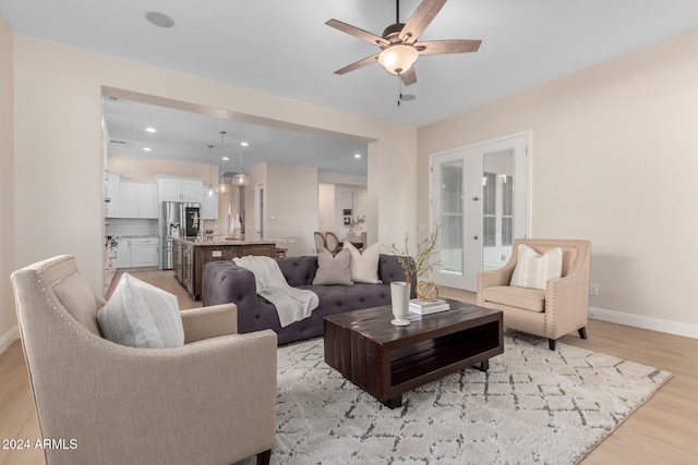 living room featuring light wood-type flooring, french doors, and ceiling fan