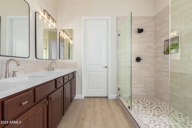 bathroom with hardwood / wood-style floors, vanity, backsplash, and a shower with shower door