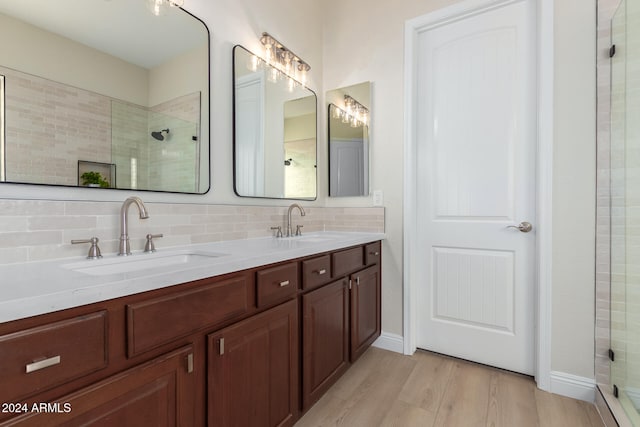 bathroom featuring walk in shower, wood-type flooring, vanity, and decorative backsplash