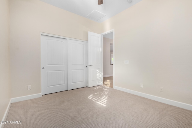 unfurnished bedroom featuring light colored carpet, ceiling fan, and a closet