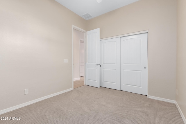 unfurnished bedroom with light carpet and a closet