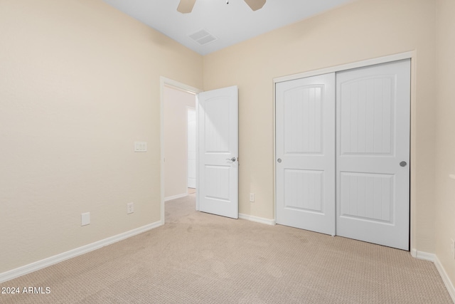 unfurnished bedroom with ceiling fan, light carpet, and a closet