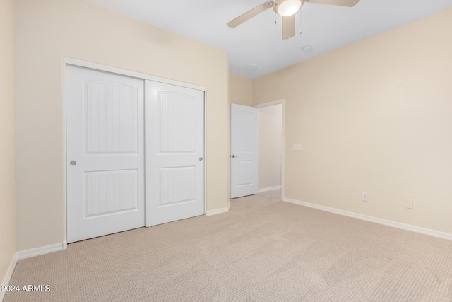 unfurnished bedroom featuring ceiling fan, light colored carpet, and a closet