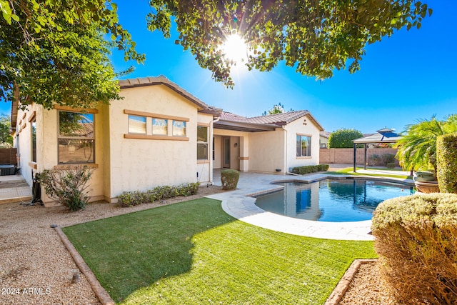 rear view of house featuring a fenced in pool, a patio area, and a lawn