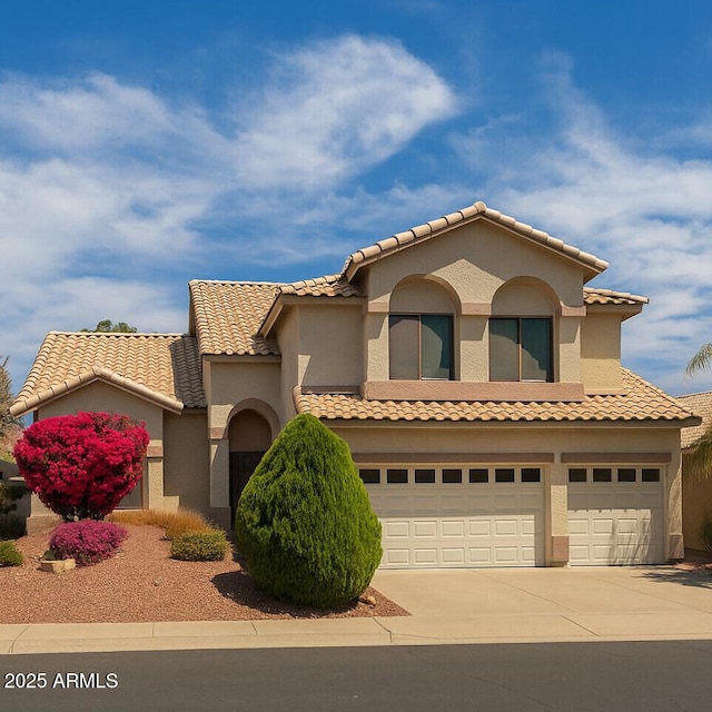 mediterranean / spanish-style house featuring concrete driveway, an attached garage, a tile roof, and stucco siding