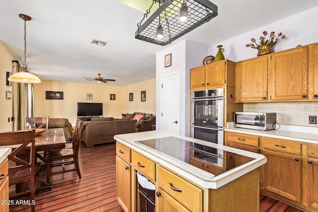 kitchen featuring backsplash, dark wood-style flooring, visible vents, appliances with stainless steel finishes, and a center island