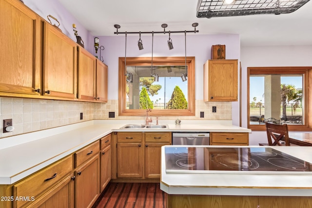 kitchen featuring stainless steel dishwasher, light countertops, a sink, dark wood finished floors, and backsplash