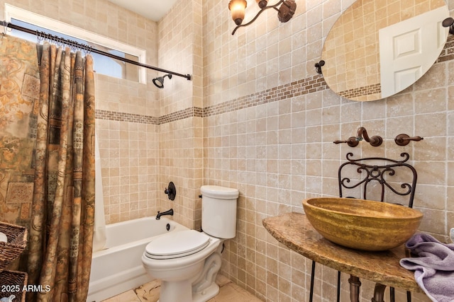 full bath featuring toilet, tile walls, shower / bath combination with curtain, and a sink