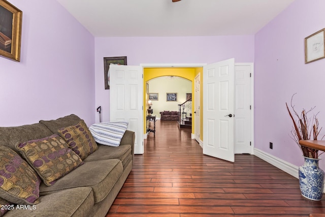 living area with arched walkways, baseboards, dark wood finished floors, and a ceiling fan