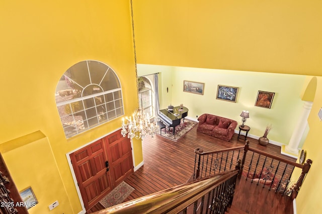 interior space with a towering ceiling, wood finished floors, and a notable chandelier