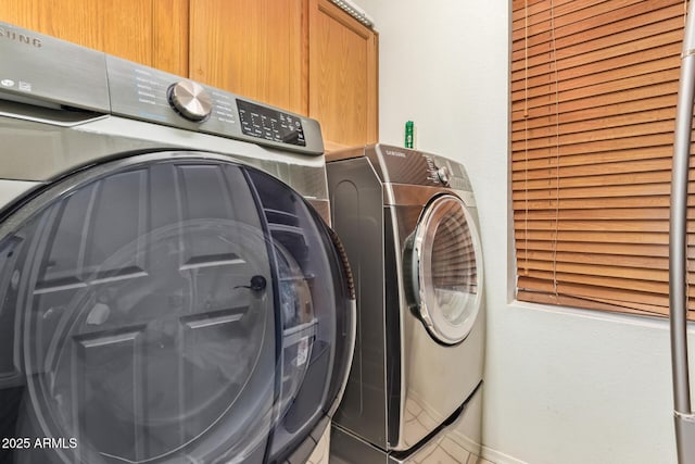 laundry area featuring baseboards, cabinet space, and washer and dryer
