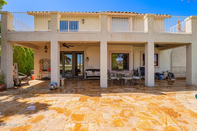 back of property featuring a ceiling fan, a patio, stucco siding, and a balcony