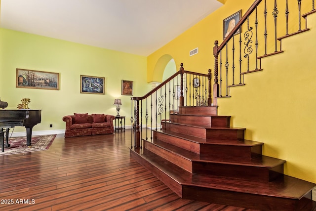 stairs featuring wood-type flooring, arched walkways, baseboards, and visible vents