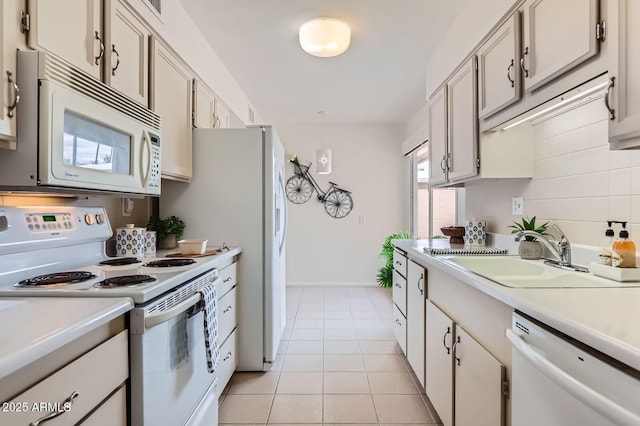 kitchen featuring a sink, white appliances, light tile patterned floors, and light countertops