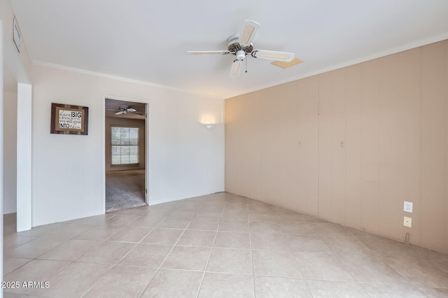 spare room featuring light tile patterned floors, a ceiling fan, and ornamental molding