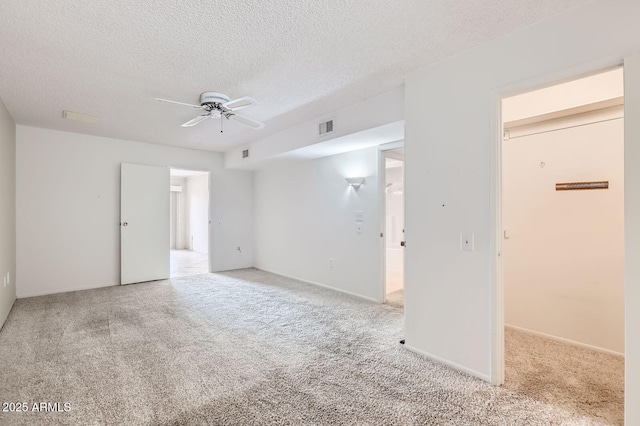 unfurnished room featuring visible vents, carpet, ceiling fan, and a textured ceiling