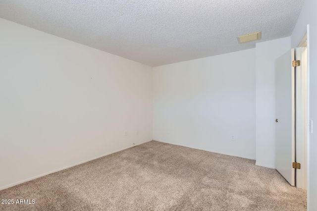 carpeted empty room with visible vents and a textured ceiling