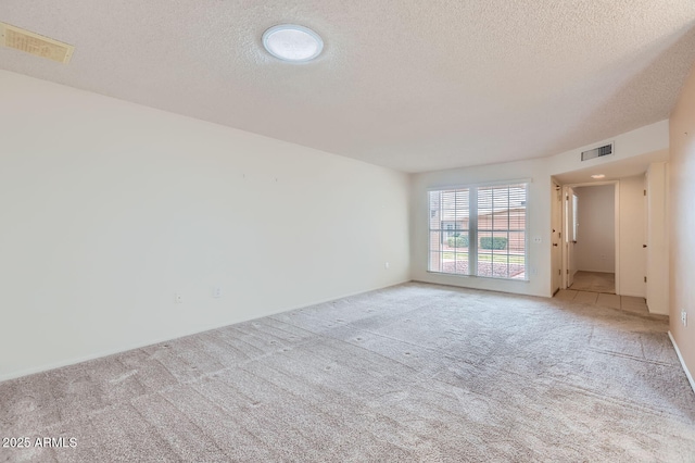 empty room with light carpet, visible vents, and a textured ceiling