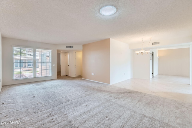 empty room with an inviting chandelier, light tile patterned floors, light colored carpet, and visible vents