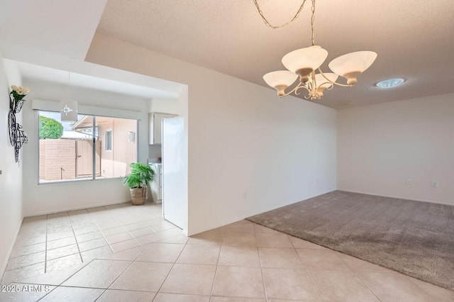 empty room featuring light tile patterned flooring, a notable chandelier, light colored carpet, and a textured ceiling