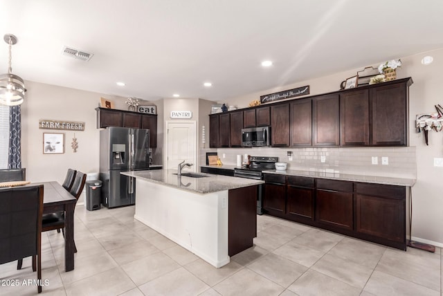 kitchen featuring sink, light stone counters, a center island with sink, appliances with stainless steel finishes, and pendant lighting