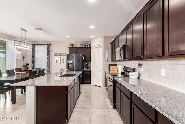 kitchen featuring decorative light fixtures, an island with sink, sink, stainless steel appliances, and light stone countertops